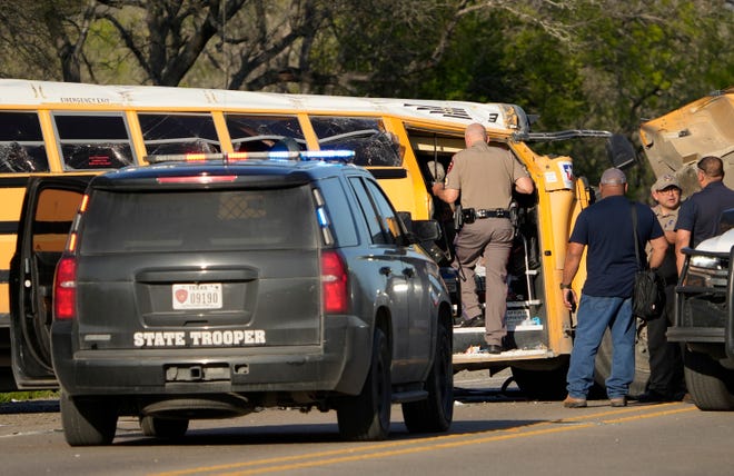 A state trooper looks at a fatal school bus crash on SH 21 near Caldwell Road Friday March 22, 2024.